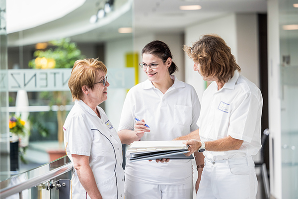 Drei Klinikmitarbeitende tauschen sich aus.