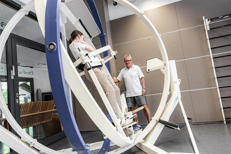 Ein Therapeut begleitet eine Patientin beim Training am SpaceCurl.