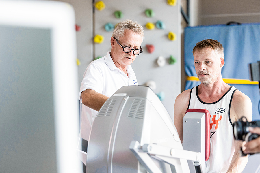 Ein Patient und ein Therapeut an einem Trainingsgerät.